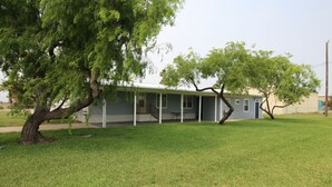 A single-story house with a porch, surrounded by a well-maintained lawn. - 334 N Harbor - Perfect Place to getaway & relax! (Port Mansfield)