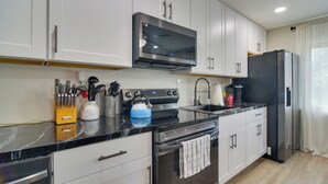 A modern kitchen with white cabinets, a black refrigerator, a stainless steel range, and a microwave. - 13 Mi to Busch Gardens: Tampa Gem w/ Grill & Yard (Tampa)