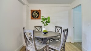 A dining area with a round table, four chairs, a potted plant, and a dartboard on the wall. - 13 Mi to Busch Gardens: Tampa Gem w/ Grill & Yard (Tampa)