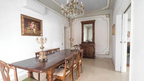 A dining room with a wooden table, chairs, a chandelier, and a mirror on the wall.