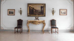 A room with two chairs, a table, and three framed pictures on the wall.