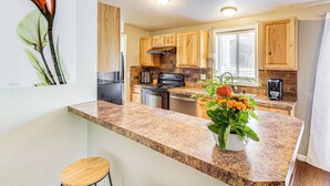 A kitchen with granite countertops, wooden cabinets, a stainless steel refrigerator, and a coffee maker. - 1 Mi to Tubbs Hill & Lake: Midtown Home w/ Yard! (Coeur d'Alene)