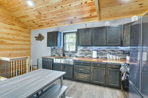 A modern kitchen with wooden ceiling, dark cabinets, and a stainless steel refrigerator.