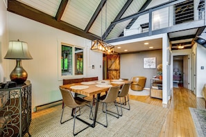 A dining area with a wooden table, chairs, and a hanging light fixture. - Blue Ridge Pkwy View & Deck: Brevard Home! (Brevard)