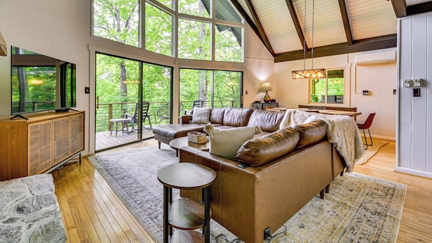 A spacious living area with a large sectional sofa, a wooden coffee table, and a stone accent piece. - Blue Ridge Pkwy View & Deck: Brevard Home! (Brevard)