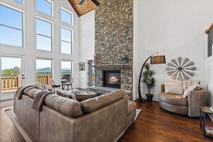 Un salón amplio con chimenea de piedra, sofás de cuero y vistas al exterior.