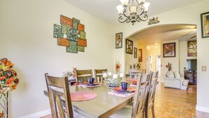 A dining area with a wooden table, chairs, and a chandelier. - Family-friendly Home w/ Fenced Yard in Victorville (Victorville)