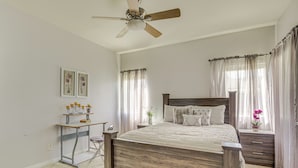 A bedroom with a wooden bed, a desk, a chair, a ceiling fan, and a window with curtains. - Family-friendly Home w/ Fenced Yard in Victorville (Victorville)