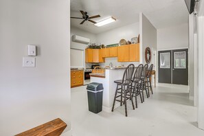 A kitchen with wooden cabinets, a ceiling fan, and a trash bin. - Charming Iowa Home: 1 Mi to Golf (Ellston)