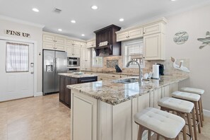 A spacious kitchen with a large island, stainless steel appliances, and a 'FINS UP' sign on the door. - Gulf Side Gated Comm with Beach Access- Fintastic by Royal Destinations (Santa Rosa Beach)