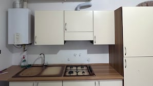 A kitchen with white cabinets, a wooden countertop, a sink, a stove, and a water heater. - Dante4 Flat Cremona Old Town (Cremona)