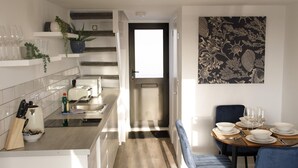 A modern kitchen with a central island, a dining area with a table and chairs, and a staircase leading to an upper level. - On the Water 5 With Free Parking By My Getaways (Brighton)