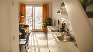 A modern kitchen with a sink, countertop, and a dining area with a table and chairs. - On the Water 5 With Free Parking By My Getaways (Brighton)