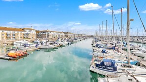 A marina with numerous boats docked along a calm waterway, surrounded by buildings with a uniform architectural style. - On the Water 5 With Free Parking By My Getaways (Brighton)
