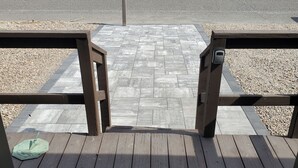Una terraza de madera con un felpudo y un parquímetro al fondo.