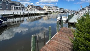Un puerto deportivo con barcos amarrados, un muelle de madera y edificios residenciales al fondo.