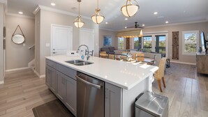 A modern kitchen with a central island, stainless steel appliances, and pendant lighting.
