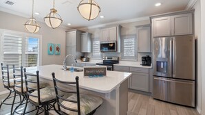 A modern kitchen with a central island, stainless steel appliances, and pendant lighting.