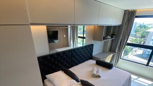 Ein modernes Schlafzimmer mit einem großen Bett, integrierten Regalen und Blick ins Freie.