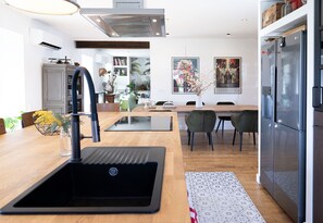 Enjoy cooking in this well-lit kitchen with a sleek sink, modern faucet, and stainless steel refrigerator.