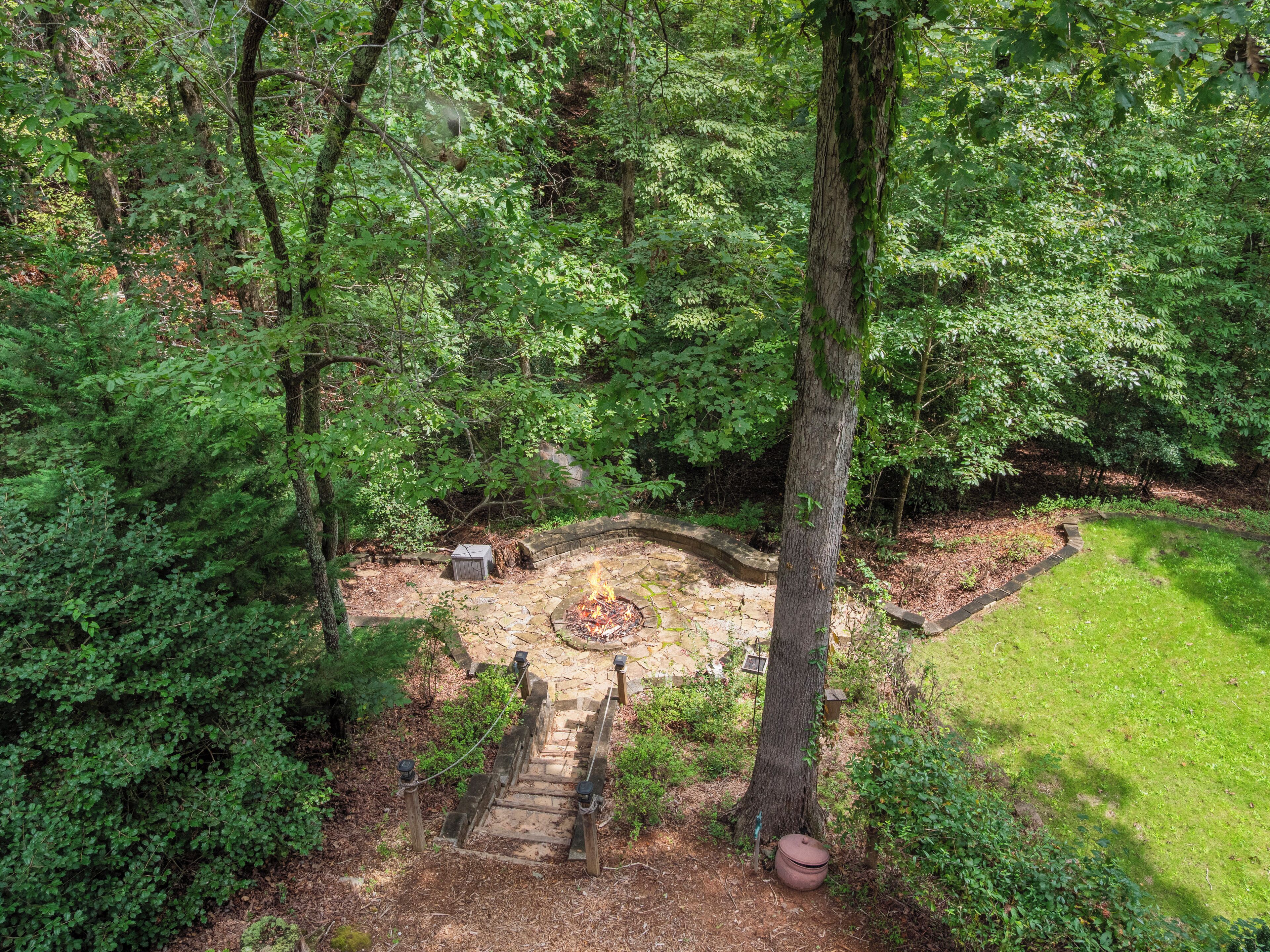 A stone staircase leading to a fire pit surrounded by dense forest.