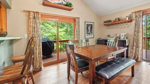 A dining area with a wooden table and chairs, a bench, and a view of greenery through large sliding glass doors. - Azure Springs- Secluded Mountain Retreat in Dahlonega. Perfect for Families! (Dahlonega)
