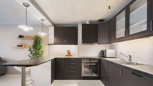 Una cocina moderna con armarios oscuros, un lavamanos de acero inoxidable y un horno empotrado.