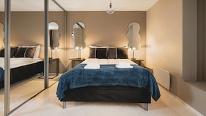 Un dormitorio moderno con una cama grande, lámparas de noche, un espejo y un radiador.
