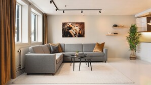 Una sala de estar moderna con un sofá gris, una mesa de centro y un ventanal con cortinas.