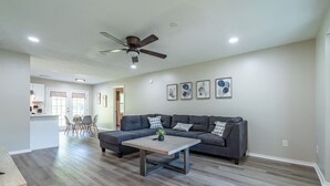 A spacious living room with a gray sectional sofa, a coffee table, and a ceiling fan. - Extended Stay 2BR • Relocation Friendly (Calhoun)
