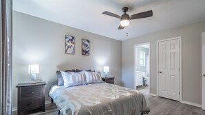 A bedroom with a bed, two bedside tables, a ceiling fan, and two wall-mounted paintings. - Extended Stay 2BR • Relocation Friendly (Calhoun)