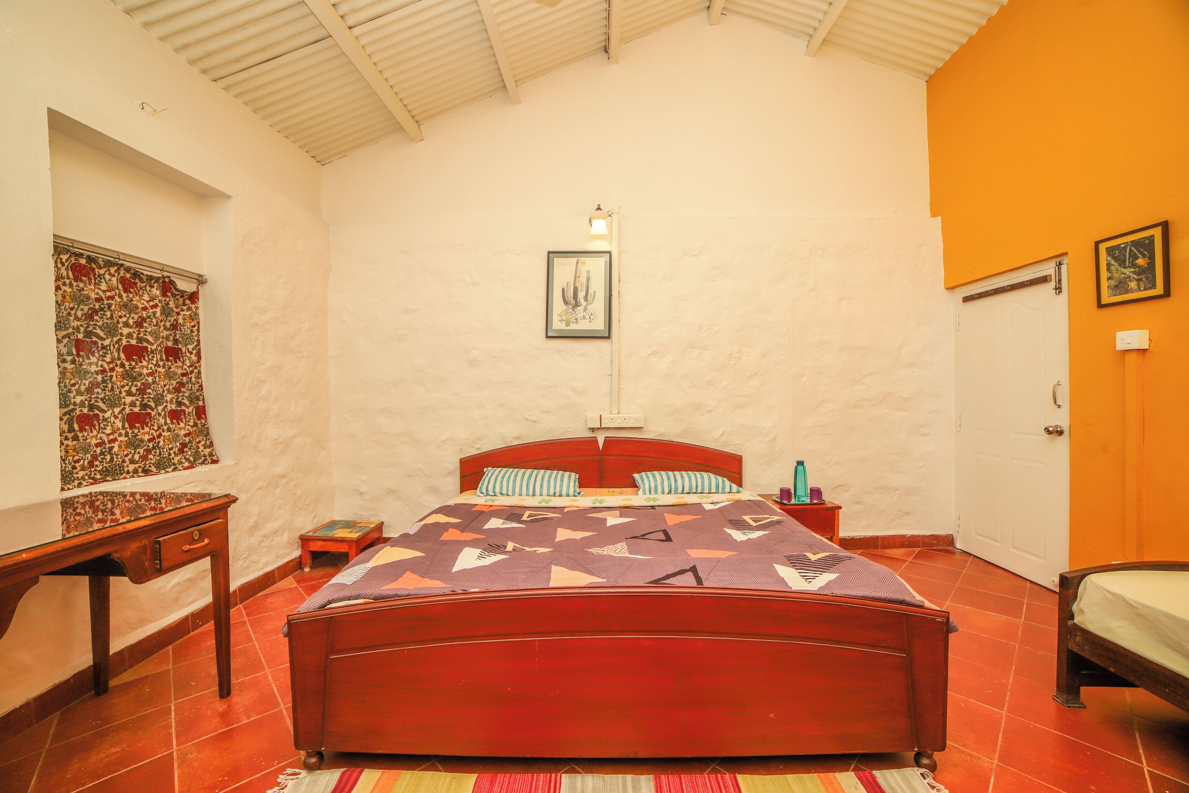 Une chambre à coucher avec un lit en bois, une table de chevet, une petite table et une lampe fixée au mur.