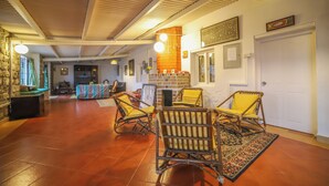 A spacious living area with a fireplace, comfortable seating, and a view of the kitchen. - Rico Retreat (Kotagiri)