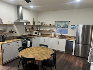 A modern kitchen with white cabinets, a stainless steel refrigerator, a microwave, and a stove. There is a wooden dining table with chairs. - Guest home 2 bedroom 2 full bath kids and adult zone.top rated place in vernal (Vernal)
