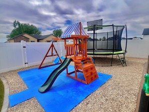 A playground with a slide and swings, a trampoline, and a covered play structure. - Guest home 2 bedroom 2 full bath kids and adult zone.top rated place in vernal (Vernal)