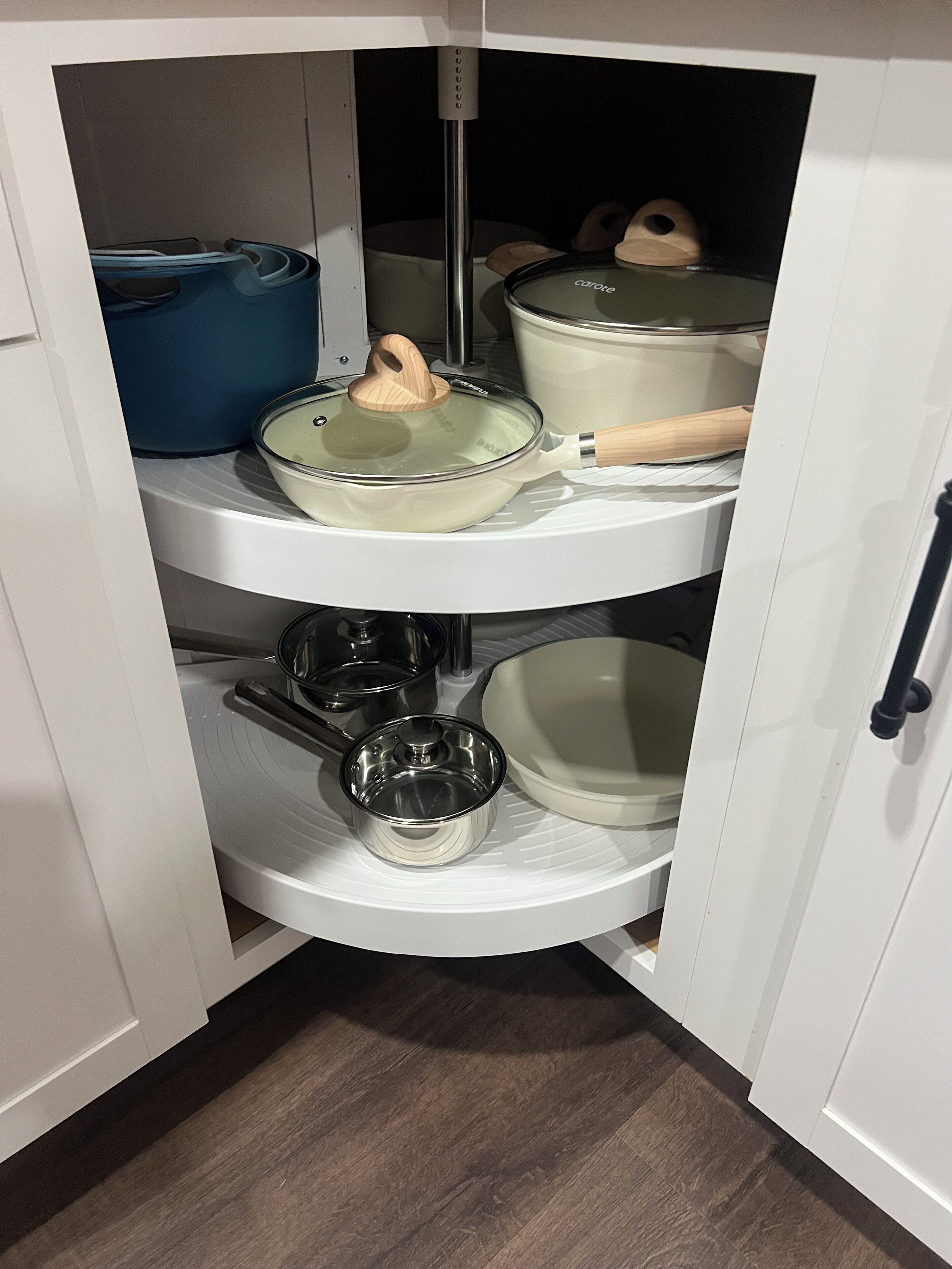 A kitchen cabinet with multiple shelves holding various kitchenware items.