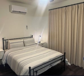 A bedroom with a bed, bedside table, lamp, air conditioning unit, and curtains. - Guest home 2 bedroom 2 full bath kids and adult zone.top rated place in vernal (Vernal)