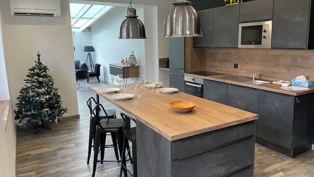 Una cocina moderna con una isla central, armarios oscuros y electrodomésticos de acero inoxidable.