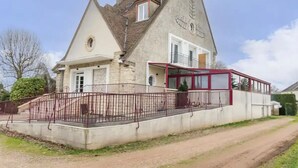 Una casa de dos plantas con fachada de piedra, un balcón rojo y una ventana pequeña.