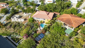 Ett flygbildsbild av ett bostadsområde med hus, en swimmingpool och solpaneler.