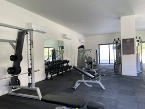 Et fitnessrum med træningsudstyr, håndvægte og en bænk.