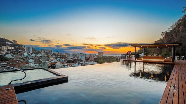 Ein Infinity-Pool mit Blick auf die Stadt bei Sonnenuntergang.