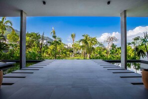 Un espacio exterior cubierto con vistas a un jardín exuberante y edificios a lo lejos.
