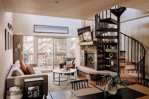 A living room with a fireplace, a sofa, a coffee table, and a staircase.