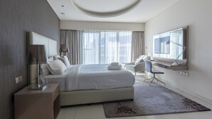 A modern hotel room with a large bed, a desk, a chair, and a large window with curtains. - Cozy 1BR with balcony Damac Towers (Dubai)