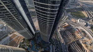 A high-rise building with a curved facade, surrounded by a well-maintained urban area with roads and greenery. - Cozy 1BR with balcony Damac Towers (Dubai)