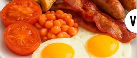 A plate of breakfast food including toast, sausages, bacon, eggs, tomatoes, and baked beans.