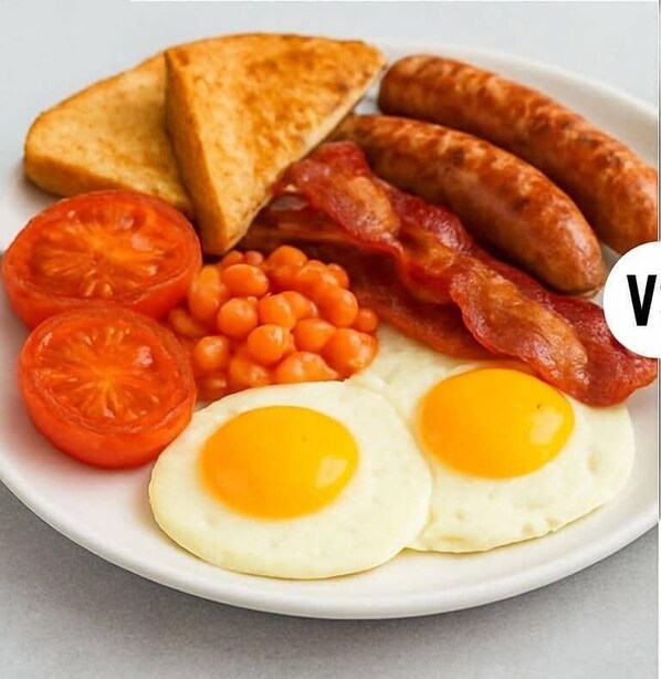 A plate of breakfast food including toast, sausages, bacon, eggs, tomatoes, and baked beans.