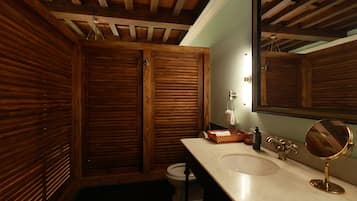 A bathroom with wooden walls, a white sink, a mirror, and a towel rack.