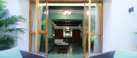 A room with a view through glass doors, a bed, a table, and a chair.